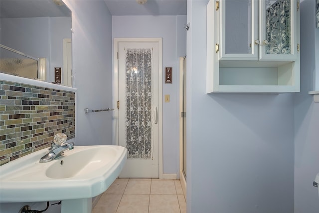 bathroom featuring tile patterned floors, sink, a shower with door, and backsplash