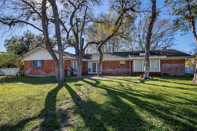 back of property with a lawn and french doors