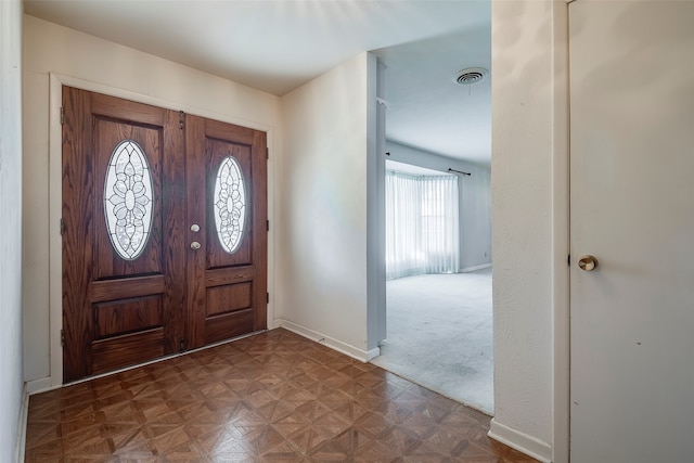 foyer with dark parquet floors and a healthy amount of sunlight