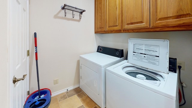 clothes washing area with cabinets and washing machine and dryer