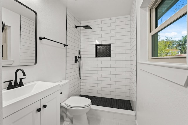 bathroom with vanity, toilet, and tiled shower