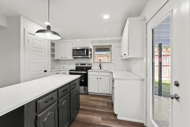 kitchen featuring sink, white cabinetry, decorative light fixtures, stainless steel appliances, and backsplash