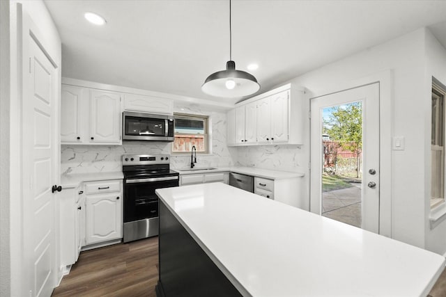 kitchen featuring white cabinetry, hanging light fixtures, sink, and appliances with stainless steel finishes