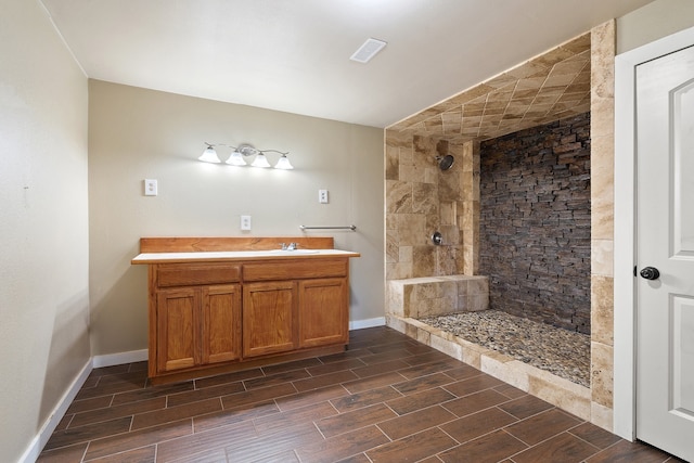 bathroom featuring tiled shower and vanity