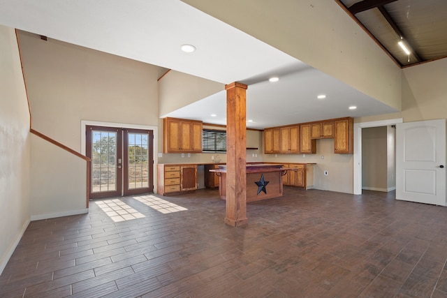 unfurnished living room featuring dark hardwood / wood-style flooring, french doors, ornate columns, and a high ceiling