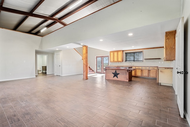 interior space with hardwood / wood-style floors, a breakfast bar, high vaulted ceiling, beam ceiling, and a kitchen island