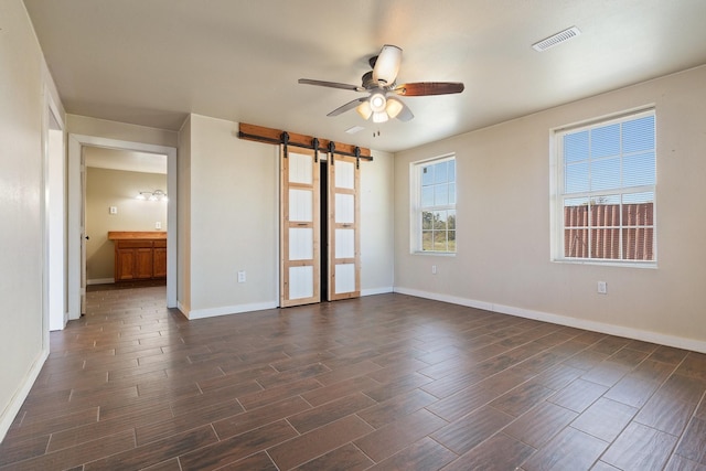 spare room with ceiling fan and a barn door