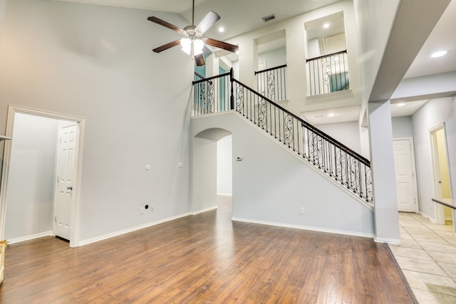 unfurnished living room with ceiling fan, light wood-type flooring, and high vaulted ceiling