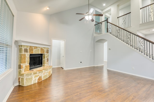 unfurnished living room featuring ceiling fan, wood-type flooring, a fireplace, and high vaulted ceiling