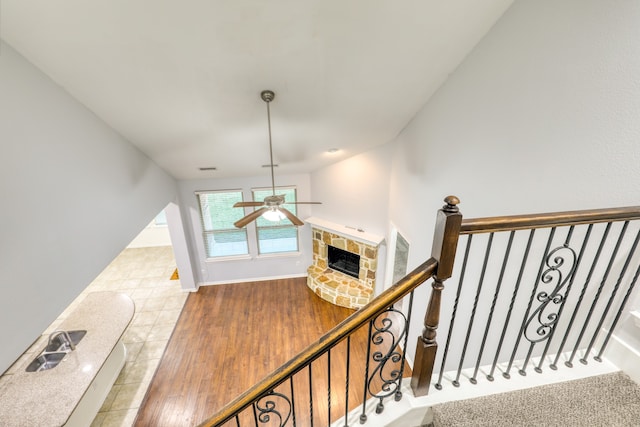 staircase featuring ceiling fan, sink, vaulted ceiling, a fireplace, and hardwood / wood-style flooring