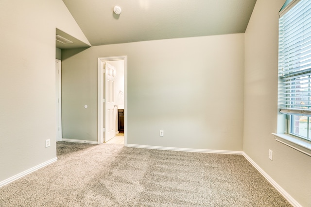 carpeted empty room featuring lofted ceiling