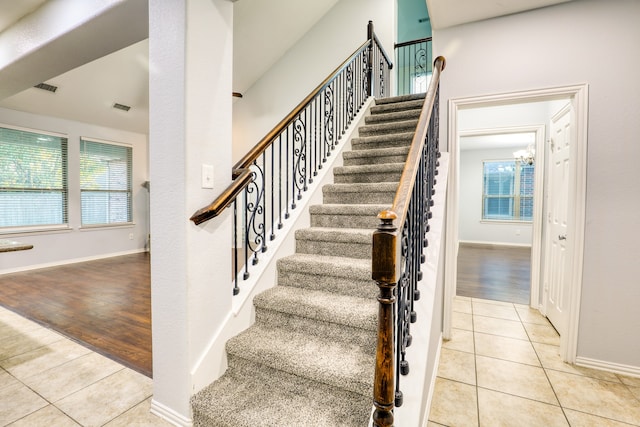 stairway featuring hardwood / wood-style floors, an inviting chandelier, and plenty of natural light