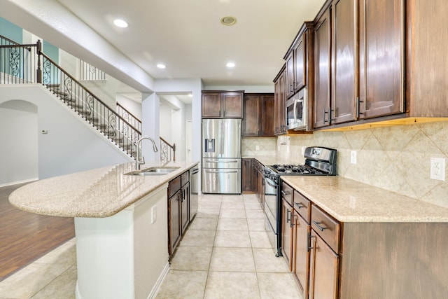 kitchen featuring light stone counters, sink, a kitchen island with sink, and appliances with stainless steel finishes