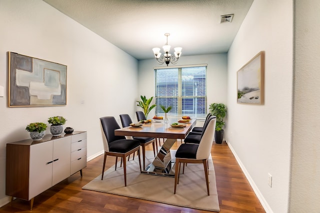 dining room featuring a textured ceiling, a notable chandelier, and dark wood-type flooring