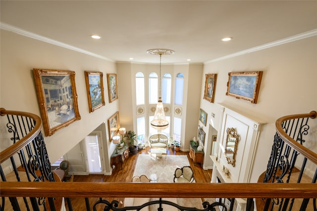 foyer entrance featuring wood-type flooring, ornamental molding, and a notable chandelier