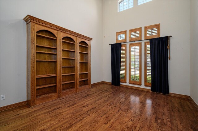 home office with dark hardwood / wood-style flooring and a high ceiling