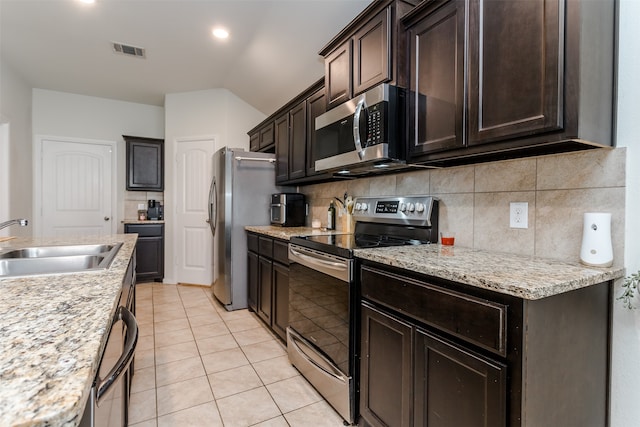 kitchen featuring sink, stainless steel appliances, light stone counters, dark brown cabinets, and light tile patterned floors