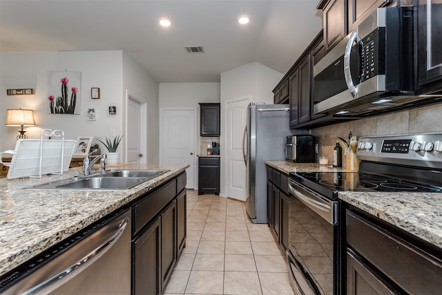 kitchen with dark brown cabinetry, sink, backsplash, light tile patterned floors, and appliances with stainless steel finishes