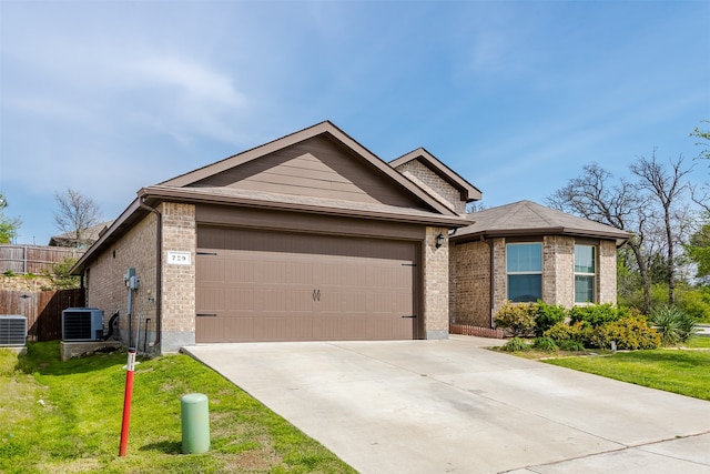 ranch-style home with cooling unit, a front yard, and a garage