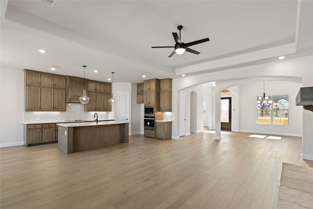 kitchen featuring a kitchen island with sink, sink, hanging light fixtures, light hardwood / wood-style flooring, and stainless steel appliances