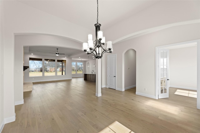 unfurnished dining area featuring ceiling fan with notable chandelier and light hardwood / wood-style flooring