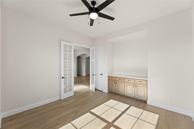 unfurnished room with ceiling fan, french doors, and light wood-type flooring