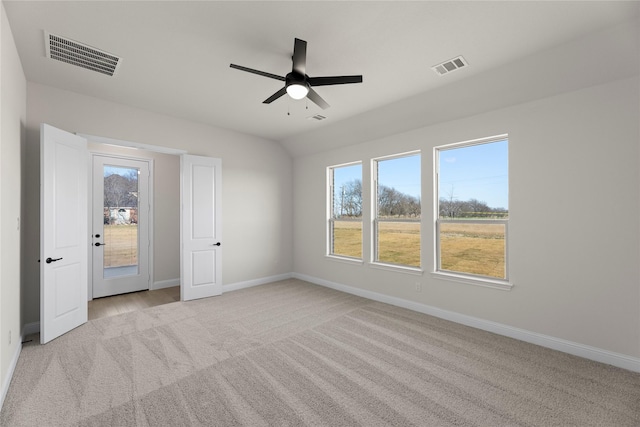 unfurnished bedroom featuring multiple windows, lofted ceiling, light colored carpet, and ceiling fan