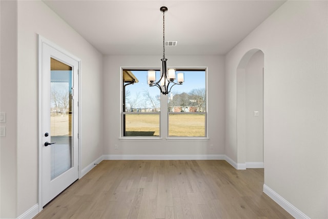 unfurnished dining area with a notable chandelier and light wood-type flooring