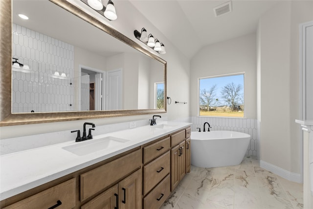 bathroom featuring a tub to relax in, vanity, and lofted ceiling