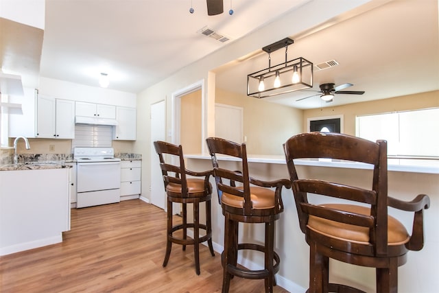 kitchen featuring pendant lighting, white electric range, ceiling fan, light wood-type flooring, and white cabinetry