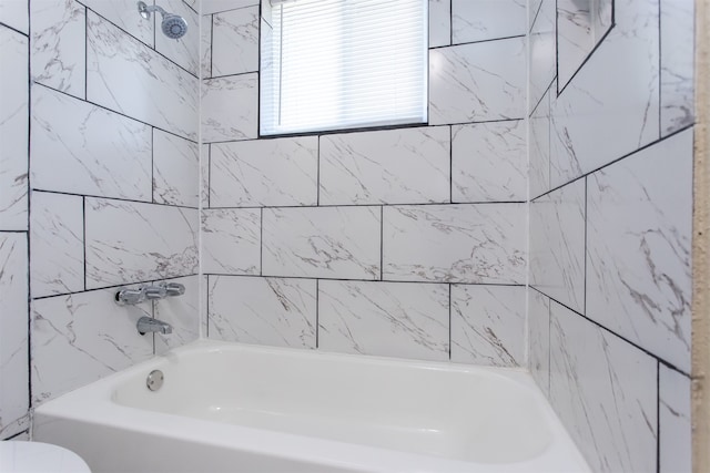 bathroom with toilet and tiled shower / bath