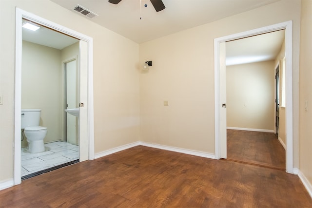 unfurnished bedroom featuring ensuite bathroom, dark hardwood / wood-style flooring, and ceiling fan