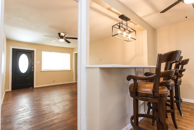 bar with dark hardwood / wood-style flooring, decorative light fixtures, and ceiling fan