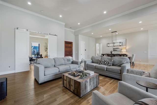 living room featuring wood-type flooring, a barn door, and crown molding