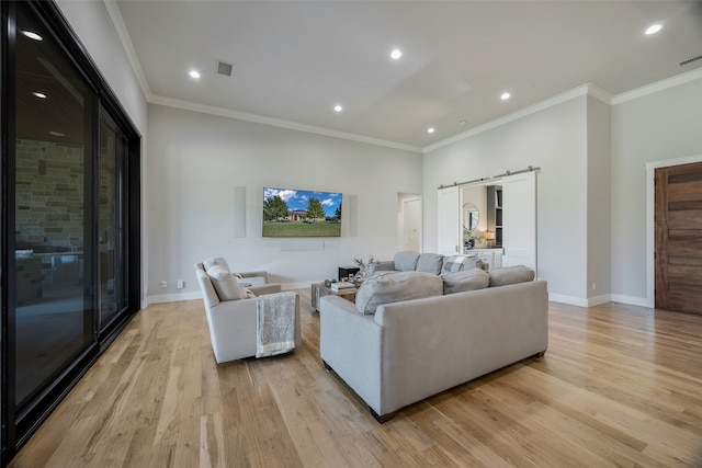 living room featuring crown molding, a barn door, and light hardwood / wood-style floors