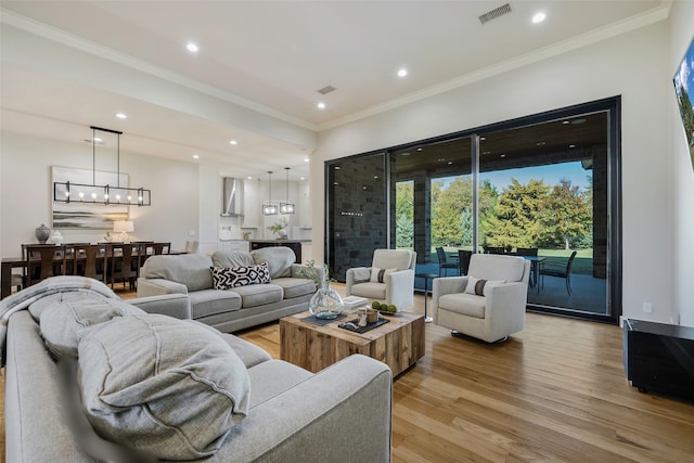 living room with crown molding, an inviting chandelier, and light hardwood / wood-style flooring