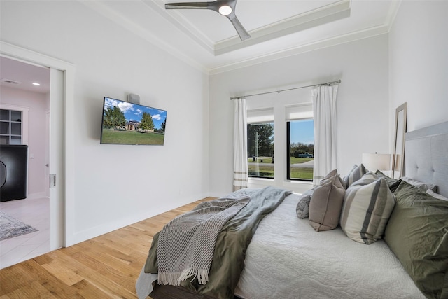 bedroom with hardwood / wood-style flooring, ceiling fan, ornamental molding, and a raised ceiling