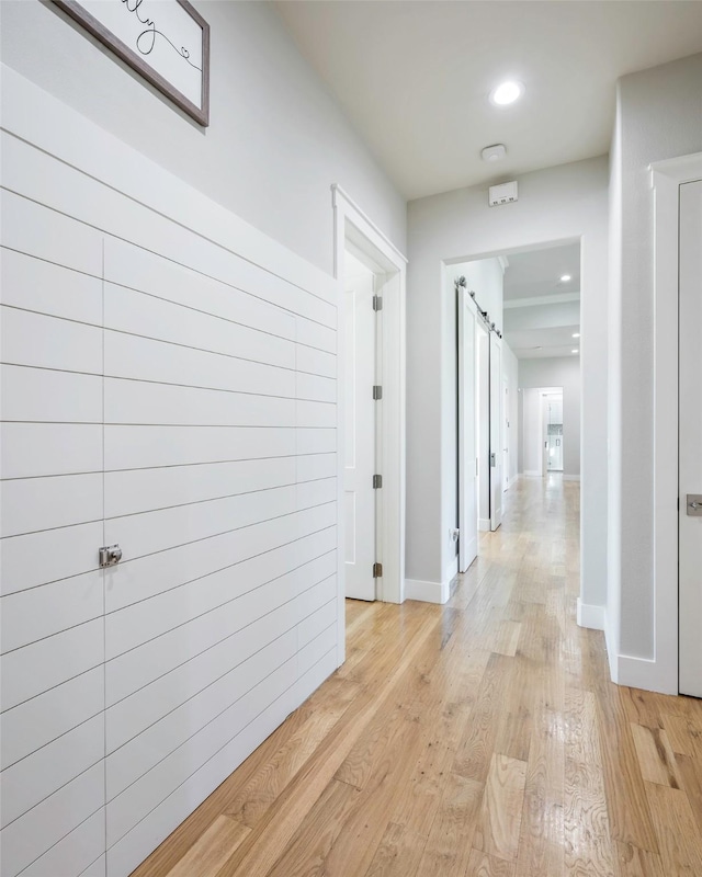 corridor with light hardwood / wood-style floors and a barn door