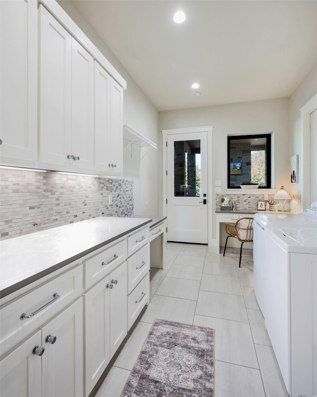 kitchen with tasteful backsplash, washer / dryer, white cabinets, and light tile patterned flooring