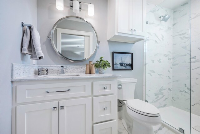 bathroom featuring a tile shower, vanity, and toilet