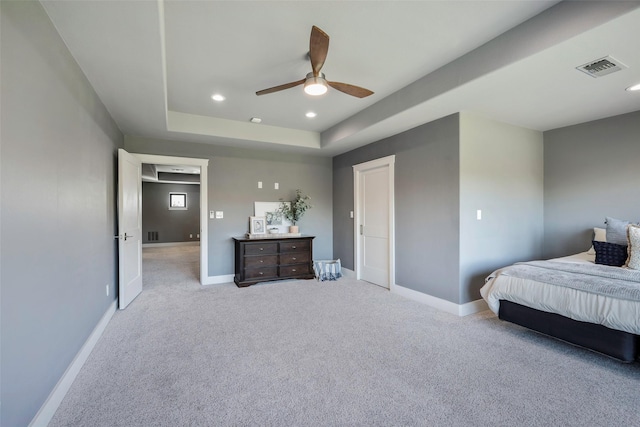 carpeted bedroom featuring a tray ceiling and ceiling fan