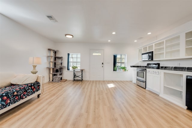 kitchen with a healthy amount of sunlight, stainless steel appliances, light hardwood / wood-style floors, and white cabinets