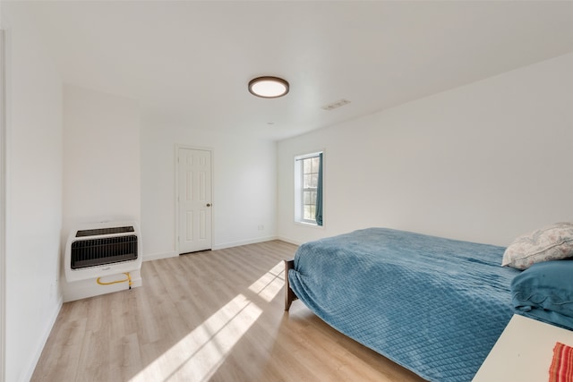 bedroom with heating unit and light hardwood / wood-style floors