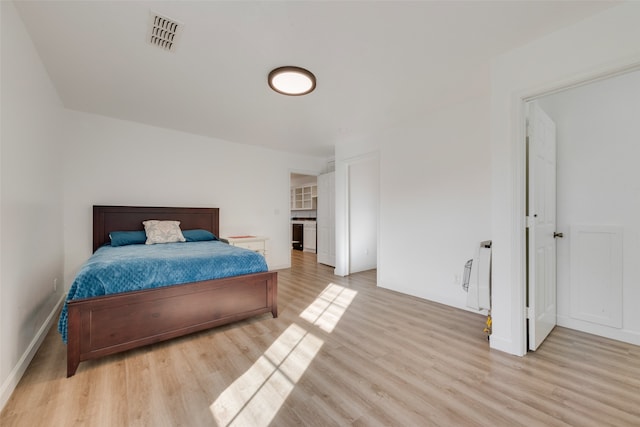 bedroom with heating unit and light hardwood / wood-style flooring