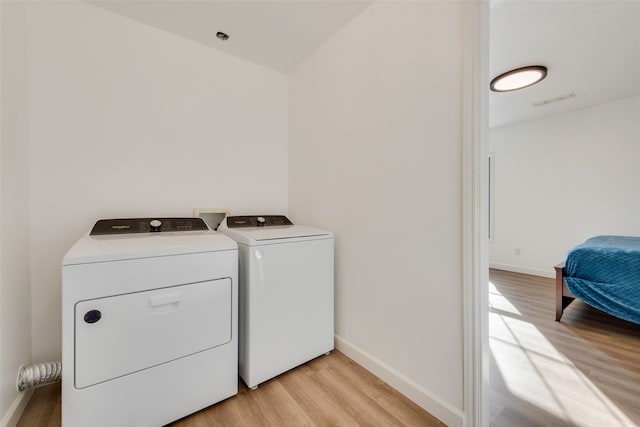 clothes washing area with light hardwood / wood-style floors and washing machine and clothes dryer