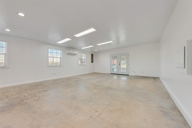 empty room with plenty of natural light, a wall mounted air conditioner, and french doors