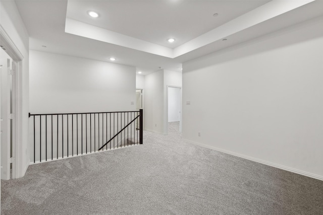 carpeted empty room with a raised ceiling