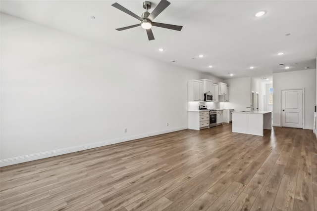 unfurnished living room featuring ceiling fan, sink, and light hardwood / wood-style flooring