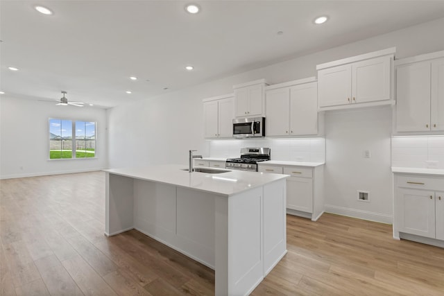 kitchen featuring stainless steel appliances, sink, a kitchen island with sink, and white cabinets