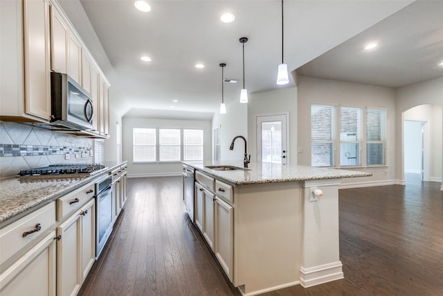 kitchen featuring sink, hanging light fixtures, dark wood-type flooring, an island with sink, and appliances with stainless steel finishes